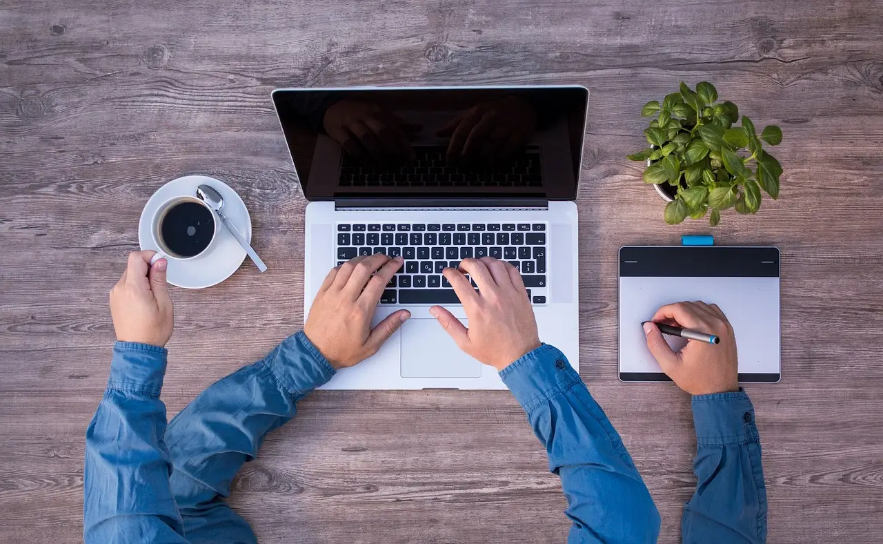 Osoba pracująca przy laptopie i równocześnie robiąca notatki – przykład multitaskingu