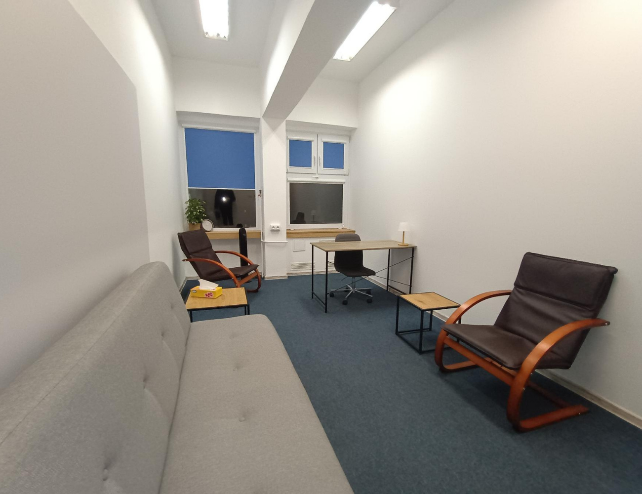 Widok gabinetu psychologicznego Michała Jaskólskiego ul. Łagiewnicka 118b w Łodzi - nowoczesne wnętrze od strony drzwi wejściowych z fotelami, biurkiem, oknami i profesjonalnym oświetleniem